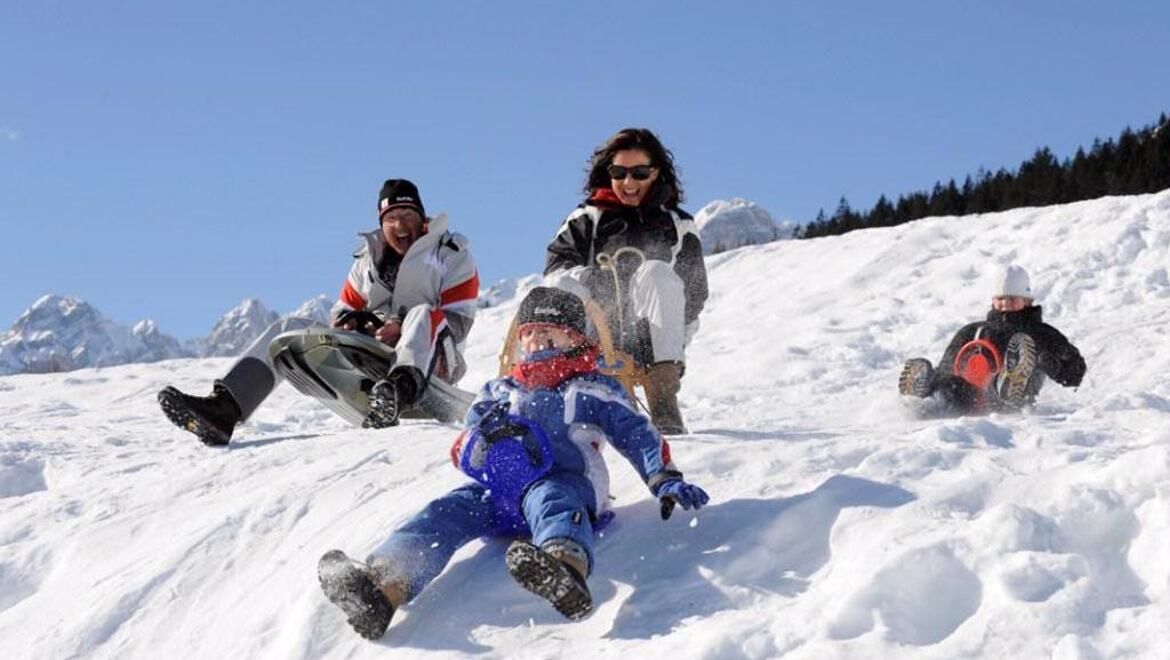 A snowy landscape with people sledding down a slope.