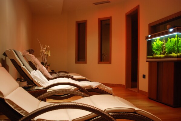 A room with reclining chairs, a large aquarium, and a wooden floor.