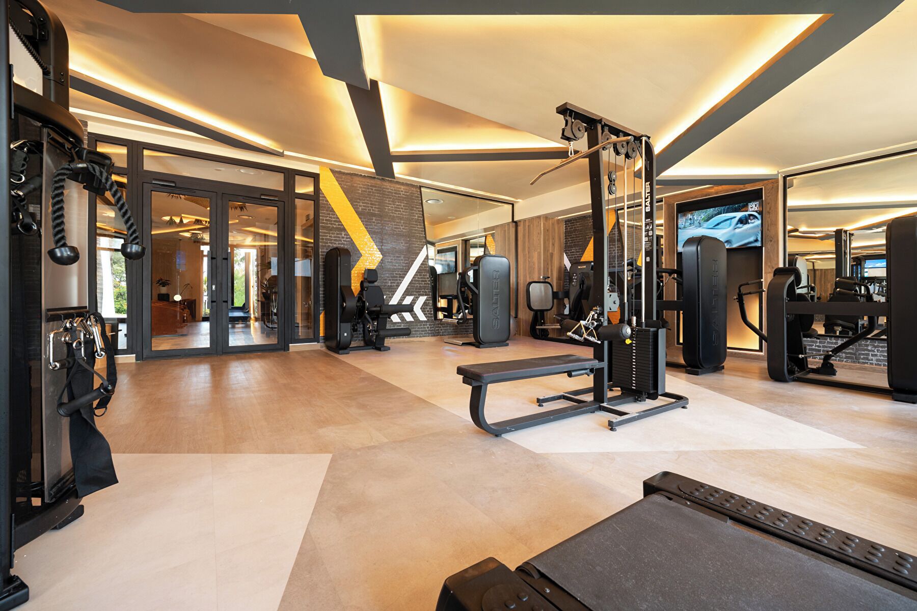 A modern gym with various exercise equipment, including a bench press, squat rack, and weight machines.