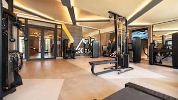 Un gimnasio moderno con varios equipos de ejercicio, incluyendo una prensa de banca, una estructura para sentadillas y máquinas de pesas.