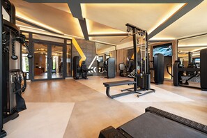 Un gimnasio moderno con varios equipos de ejercicio, incluyendo una prensa de banca, una estructura para sentadillas y máquinas de pesas.