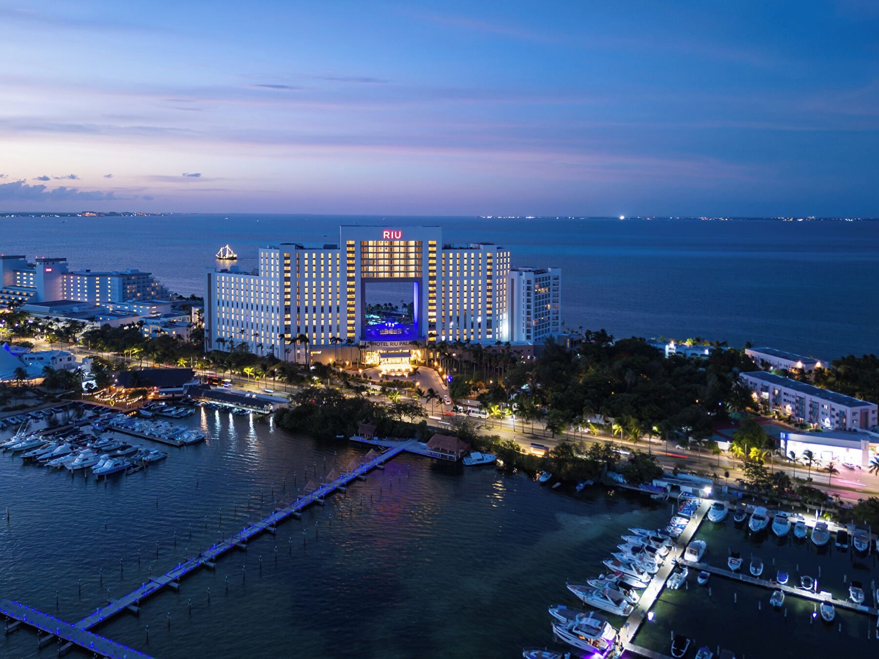 Un hotel grande con varias edificaciones, un puerto deportivo con barcos y vista al mar.