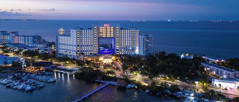 A large hotel with multiple buildings, a marina with boats, and a view of the sea.