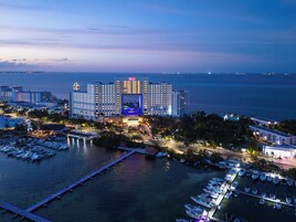 Un hotel grande con varias edificaciones, un puerto deportivo con barcos y vista al mar.