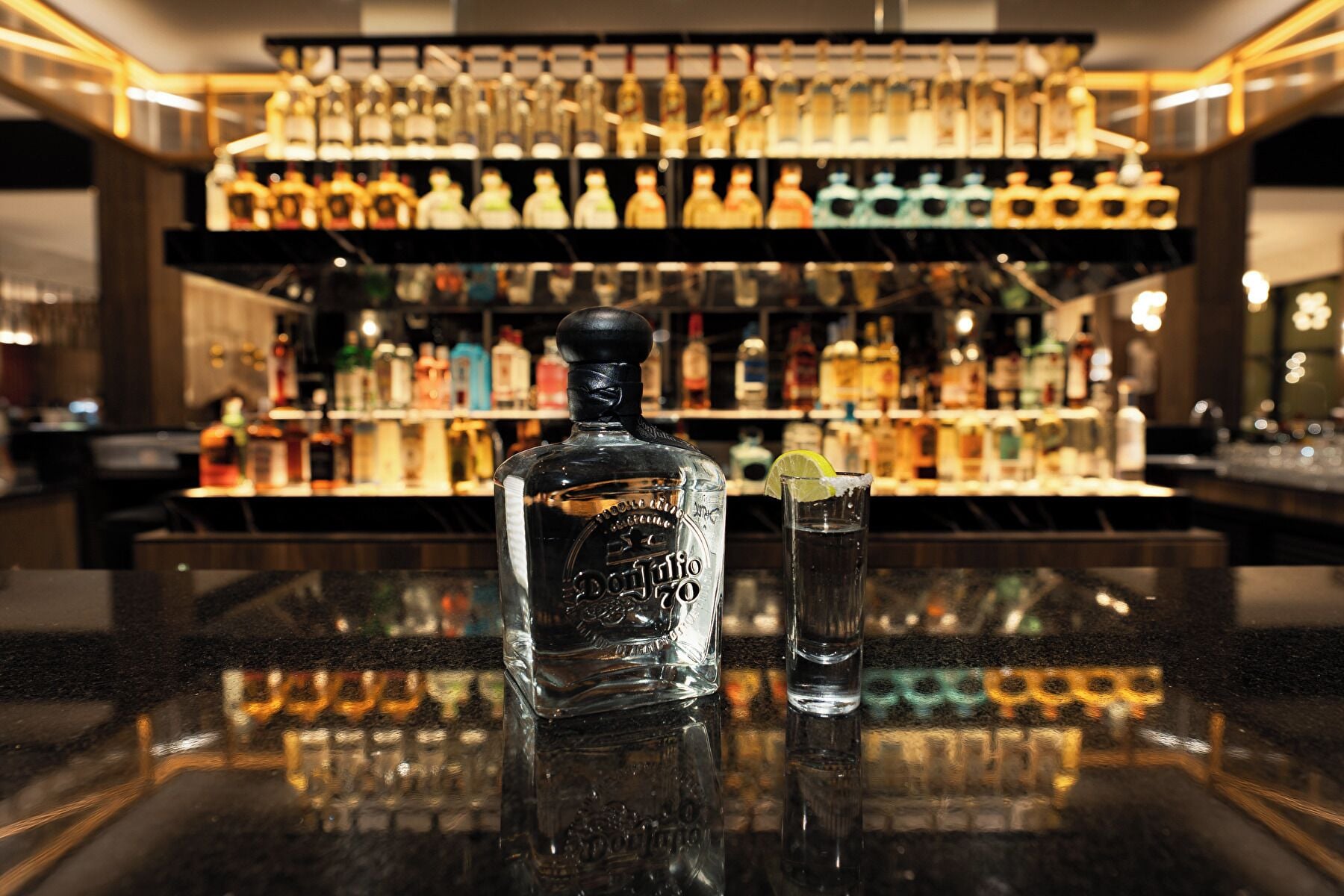 Una zona de bar con una botella de licor y un vaso de agua sobre la barra.