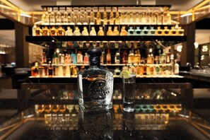 Una zona de bar con una botella de licor y un vaso de agua sobre la barra.