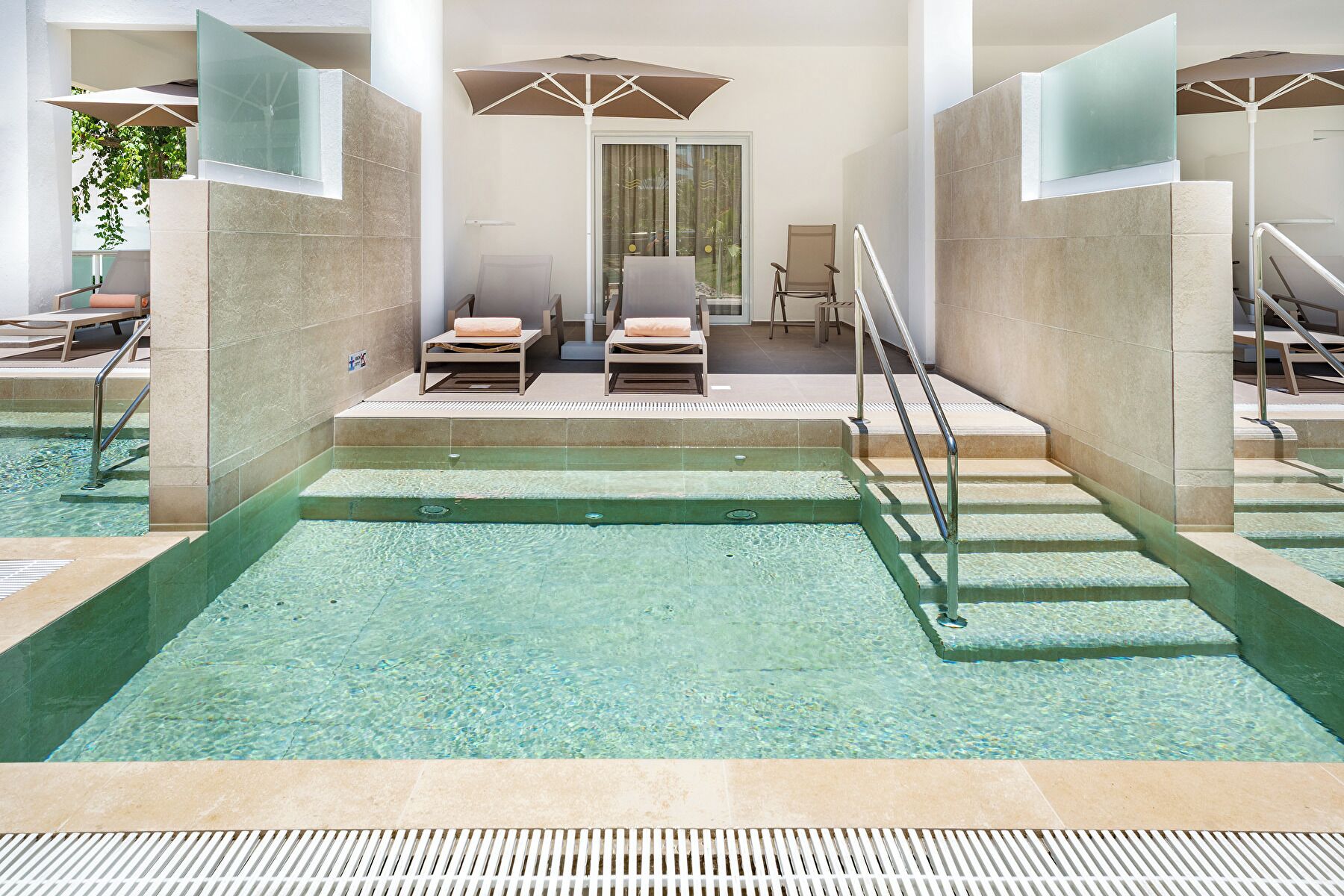 Un área de piscina con agua cristalina, sillas de descanso y sombrillas.