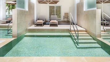 Un área de piscina con agua cristalina, sillas de descanso y sombrillas.