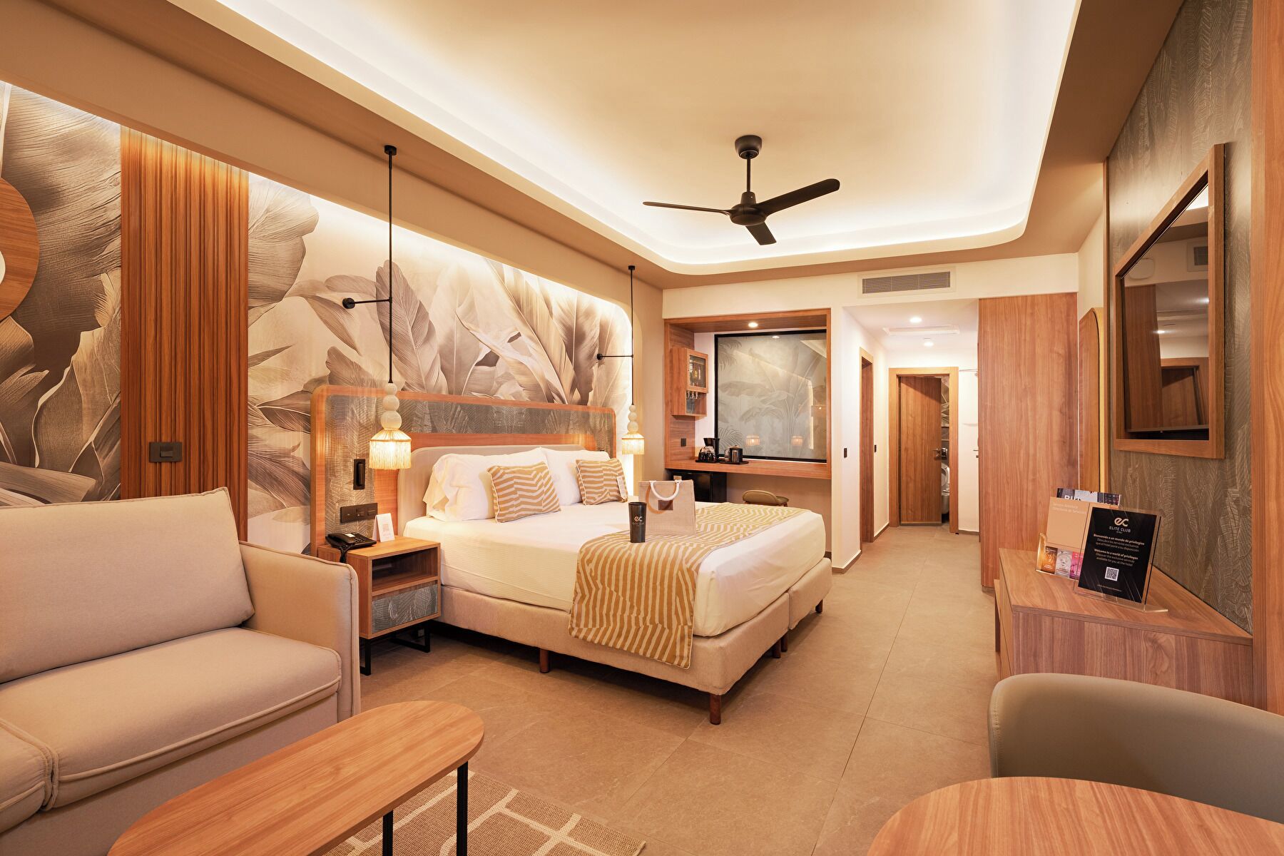Une chambre d’hôtel équipée d’un lit, d’un canapé, d’un bureau, d’un ventilateur de plafond et d’un grand miroir.