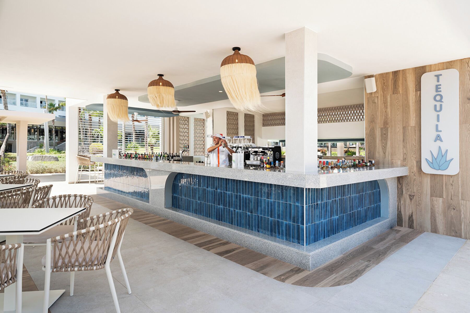 A bar area with a counter, bar stools, and a sign that reads 'TEQUILA'.