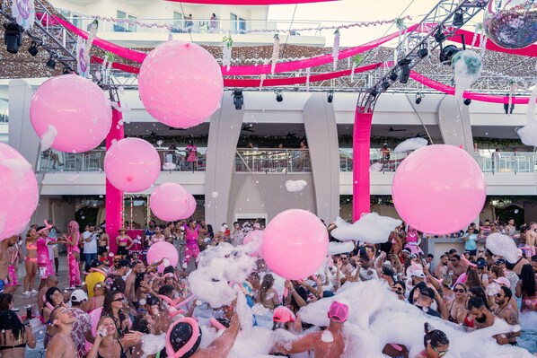 A crowded indoor event with pink decorations and large balloons. - Hotel Riu Palace Peninsula - All Inclusive (Cancun)