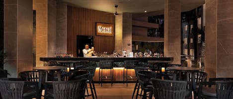 Un espace bar avec un barman, plusieurs tables et un comptoir.