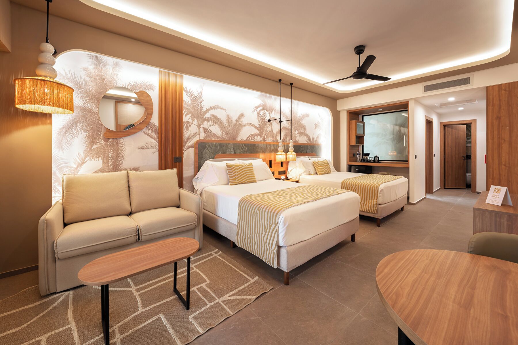 Een moderne hotelkamer met een bank, twee bedden, een tafeltje en een televisie.