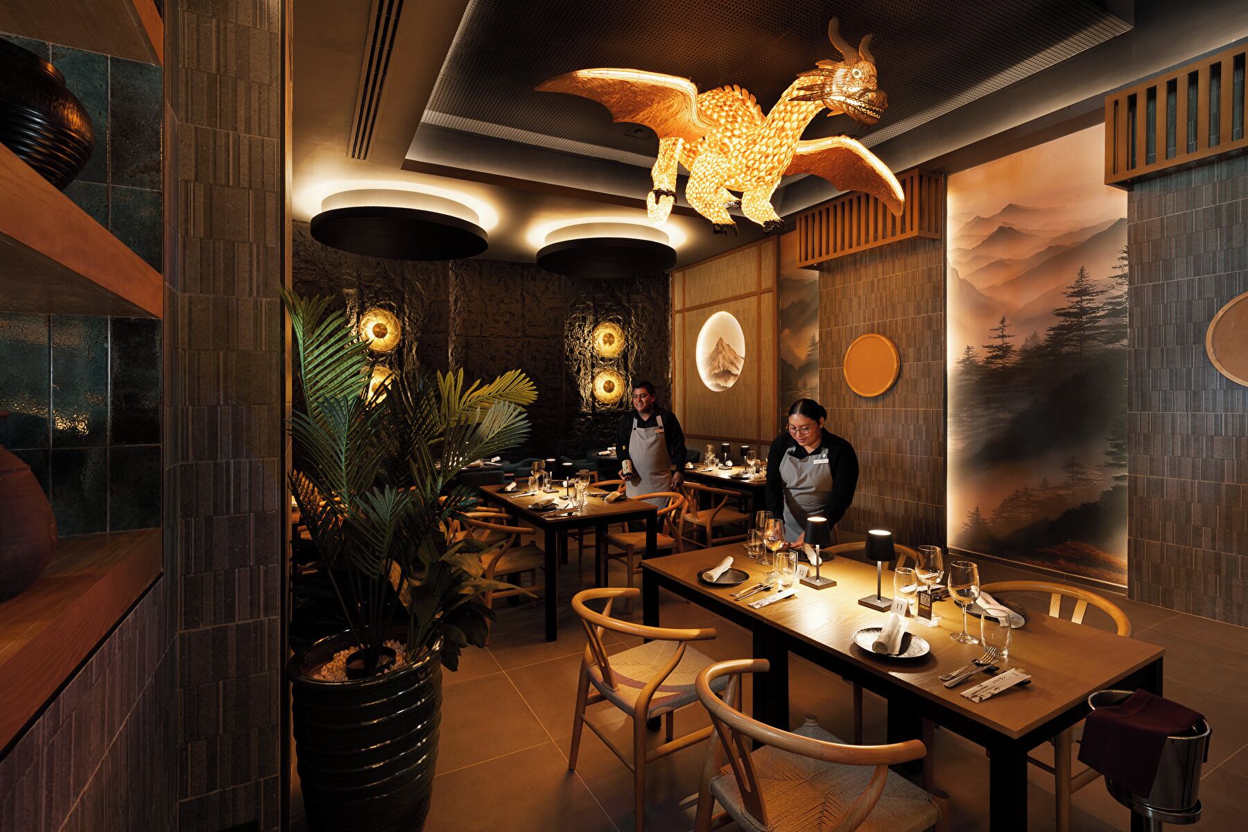 Interior de restaurante con mesas y sillas de madera, y una lámpara decorativa en el techo.