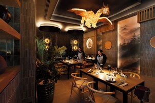 Interior de restaurante con mesas y sillas de madera, y una lámpara decorativa en el techo.
