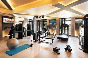 A well-equipped home gym with various exercise machines, a yoga mat, and dumbbells. - Hotel Riu Palace Peninsula - All Inclusive (Cancun)