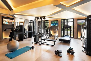 Un gimnasio doméstico bien equipado con varias máquinas de ejercicio, una colchoneta de yoga y mancuernas.