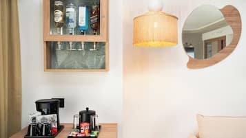 A room with a wooden-framed liquor cabinet, a table with coffee-making equipment, a hanging lamp, and a round mirror.