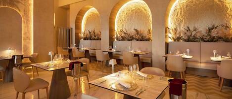 Un restaurant doté de nombreuses tables, de chaises et d’un mur chaleureux, illuminé d’une lumière douce.