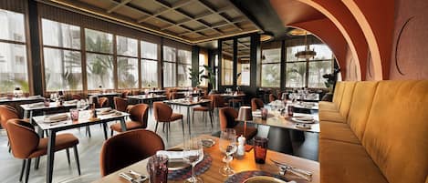 Un interior de restaurante con varias mesas, sillas y una zona de estar.
