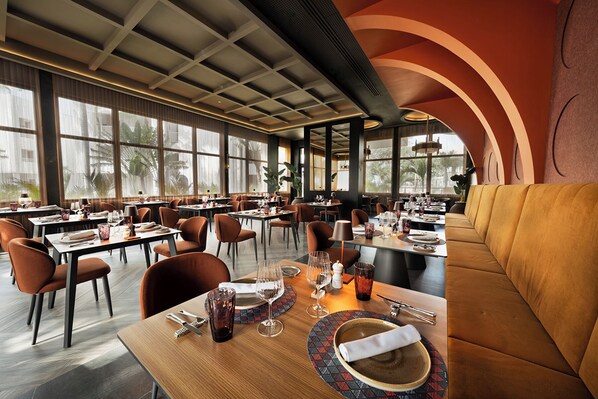 A restaurant interior with multiple dining tables, chairs, and a seating area.