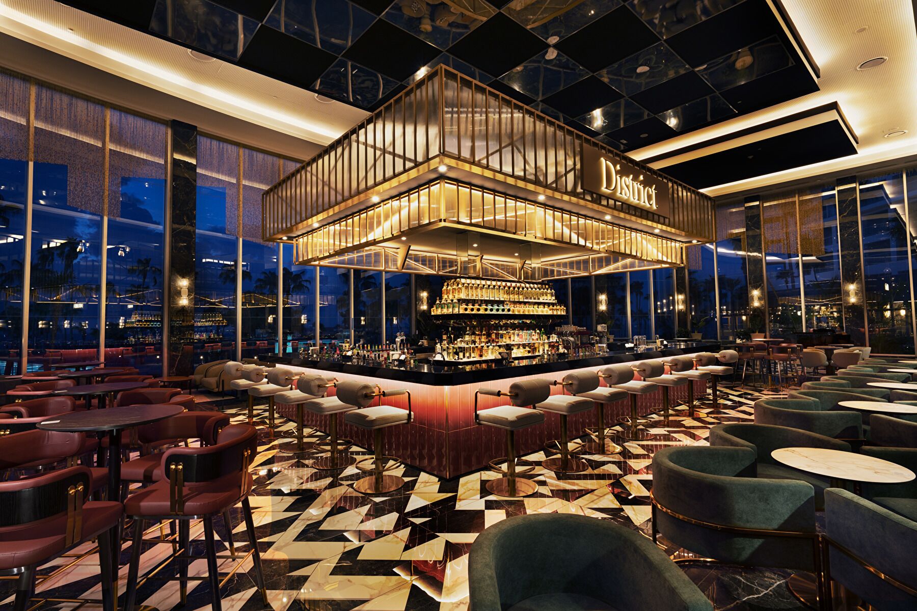 Een barruimte met een hoge plafond, een centrale bar en zitgedeeltes.