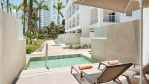 Un área de piscina con sillones de descanso y una vista despejada de un edificio de hotel al fondo.