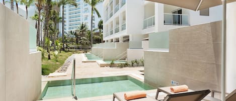 A pool area with lounge chairs and a clear view of a hotel building in the background.