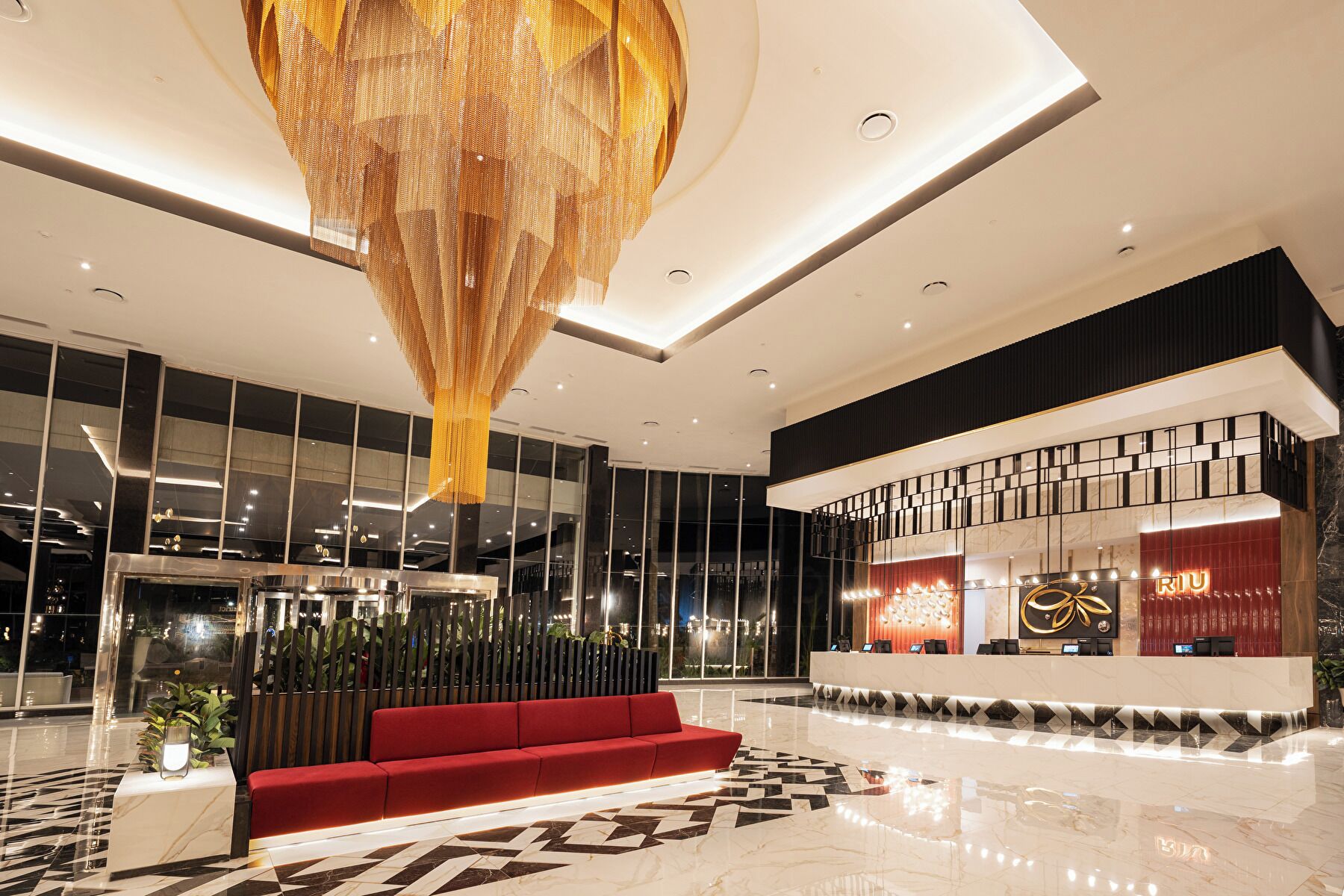 Eine moderne Hotellobby mit einer Rezeption, einem roten Sofa und einer großen Chandelier.