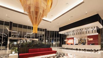 Eine moderne Hotellobby mit einer Rezeption, einem roten Sofa und einer großen Chandelier.