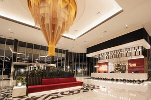 Un moderno hall de hotel con un mostrador de recepción, un sofá rojo y una gran araña.