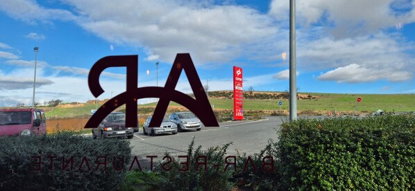 A parking lot with cars and a red sign with white text. - Villa De Los Arcos (Los Arcos)