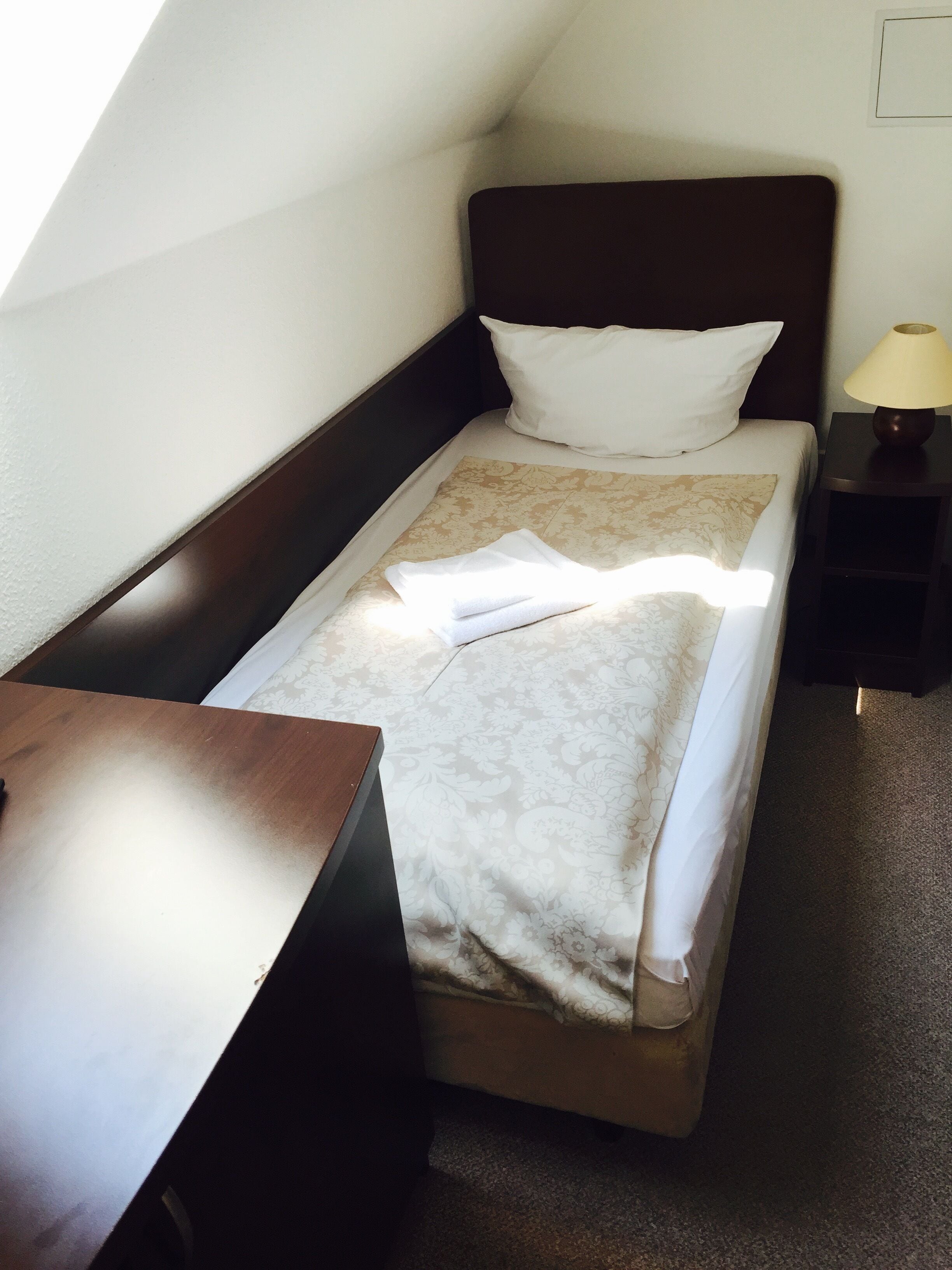 A single bed with a headboard, a bedside table, and a lamp.