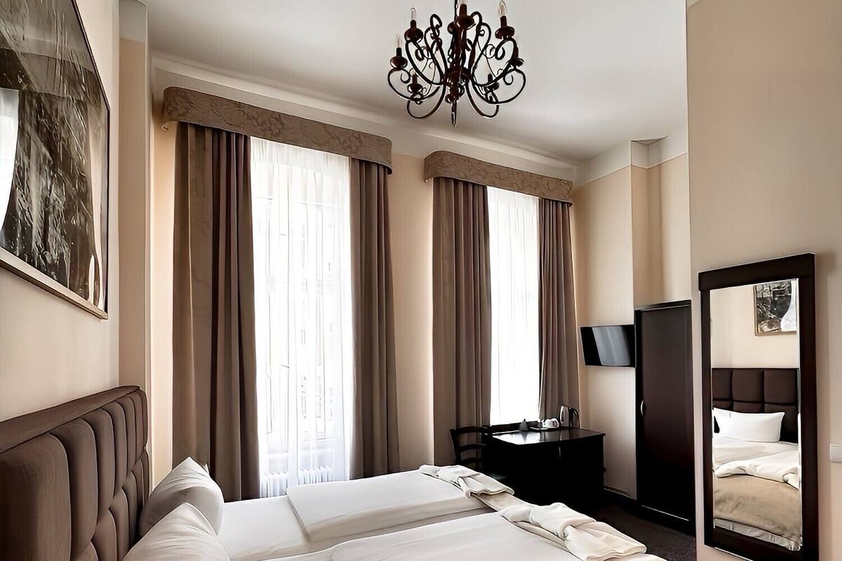 Una camera d'albergo con un letto grande, una scrivania con una sedia, un televisore e un lampadario.