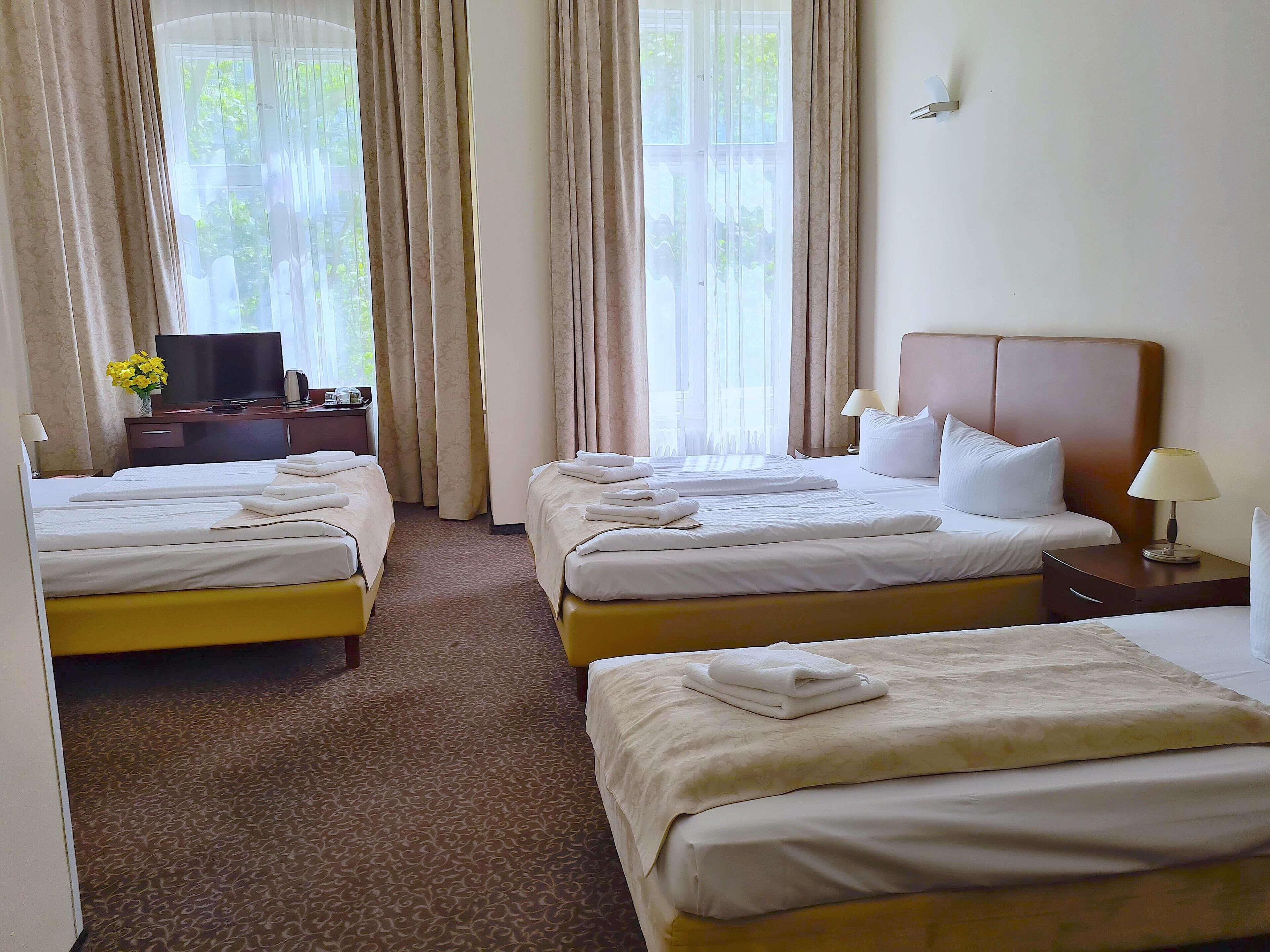 A hotel room with two beds, a TV, and a desk with a lamp.