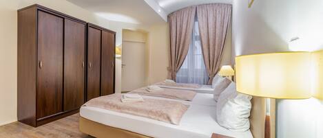 Habitación de hotel con una cama grande, un armario de madera y una lámpara de noche.