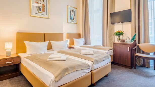 A hotel room with two beds, a flat-screen TV, a desk with a chair, and artwork on the walls. - Upper Room Hotel Kurfurstendamm (Berlin)