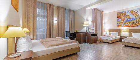 Una habitación de hotel con una cama grande, un escritorio, una computadora y dos camas más pequeñas.