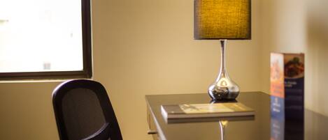 A desk with a lamp, a chair, and a window.