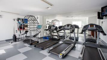 Ett gym med löpband, en trappmaskin och styrketräningsmaskiner.