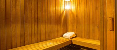 Una sauna con bancos de madera y un banco con toallas.