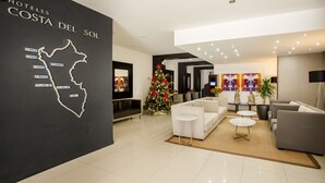 A modern hotel lobby with a map of Costa del Sol, a Christmas tree, and contemporary furniture. - Wyndham Costa del Sol Chiclayo - Chiclayo (Chiclayo)
