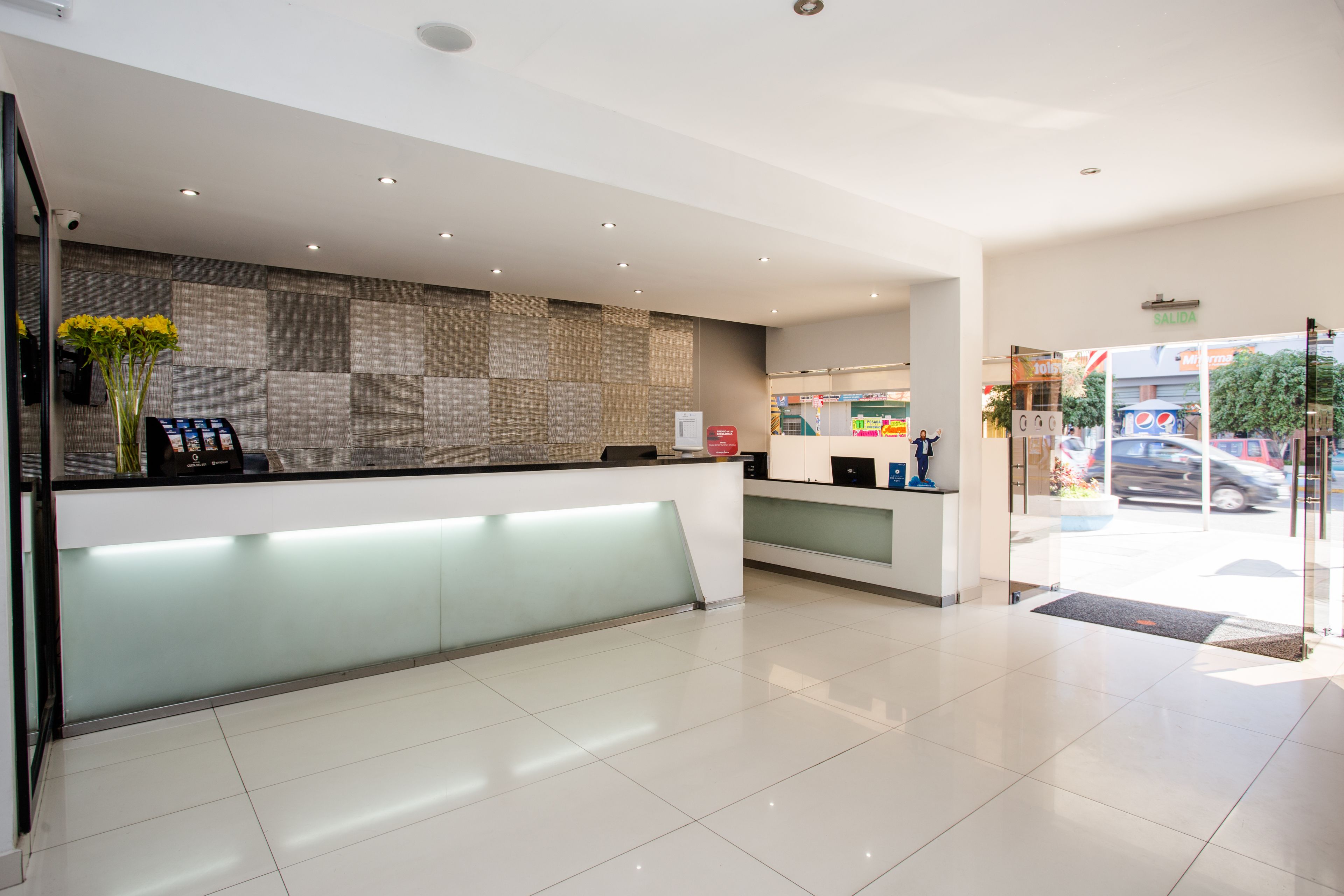 A modern reception area with a glass partition, a reception desk, and a wall with patterned tiles.