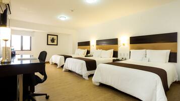 A hotel room with three beds, a desk, and a chair.
