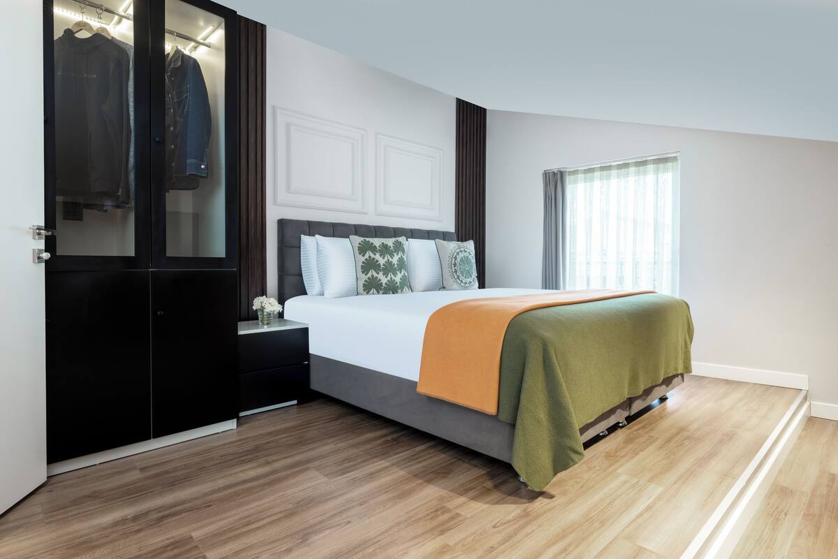 Quarto com cama, guarda-roupa, mesa de cabeceira e janela.