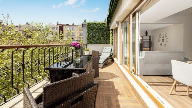 A balcony with wicker furniture, a glass table, and a view of the city. - Nardi Nişantaşı (Istanbul)