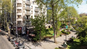 A multi-story hotel with balconies, a parking area with scooters, and a park with benches. - Nardi Nişantaşı (Istanbul)