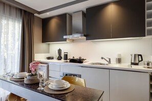 A modern kitchen with a central island, stainless steel appliances, and a dining area with a table set for two.