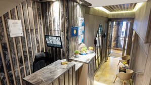 A reception desk with a marble counter, a digital screen, and a seating area with chairs and a small table. - Nardi Nişantaşı (Istanbul)