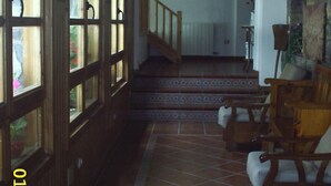 A hallway with wooden doors, a staircase, and a fan on the ceiling. - Hotel Gabarre (Broto)